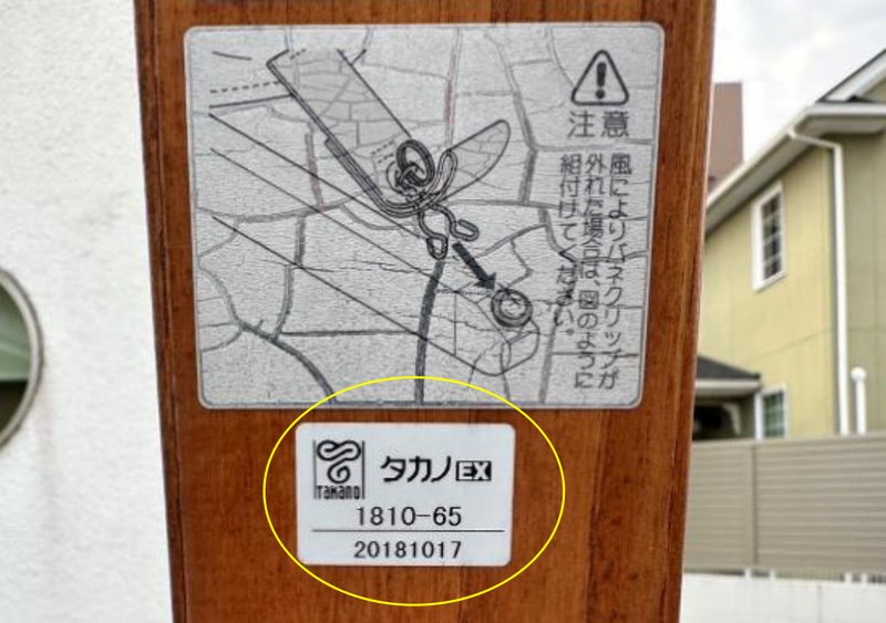 パラソルの支柱の写真。注意書きのステッカーの下にあるシールを黄色の丸で囲んでいる